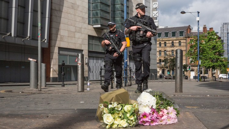 MANCHESTER, ENGLAND - MAY 23: Armed police patrol on Shudehill walking past the first floral tributes to the victims of the terrorist attack on Shudehill, May 23, 2017 in Manchester, England. An explosion occurred at Manchester Arena as concert goers were leaving the venue after Ariana Grande had performed. Greater Manchester Police are treating the explosion as a terrorist attack and have confirmed 22 fatalities and 59 injured. (Photo by Christopher Furlong/Getty Images)