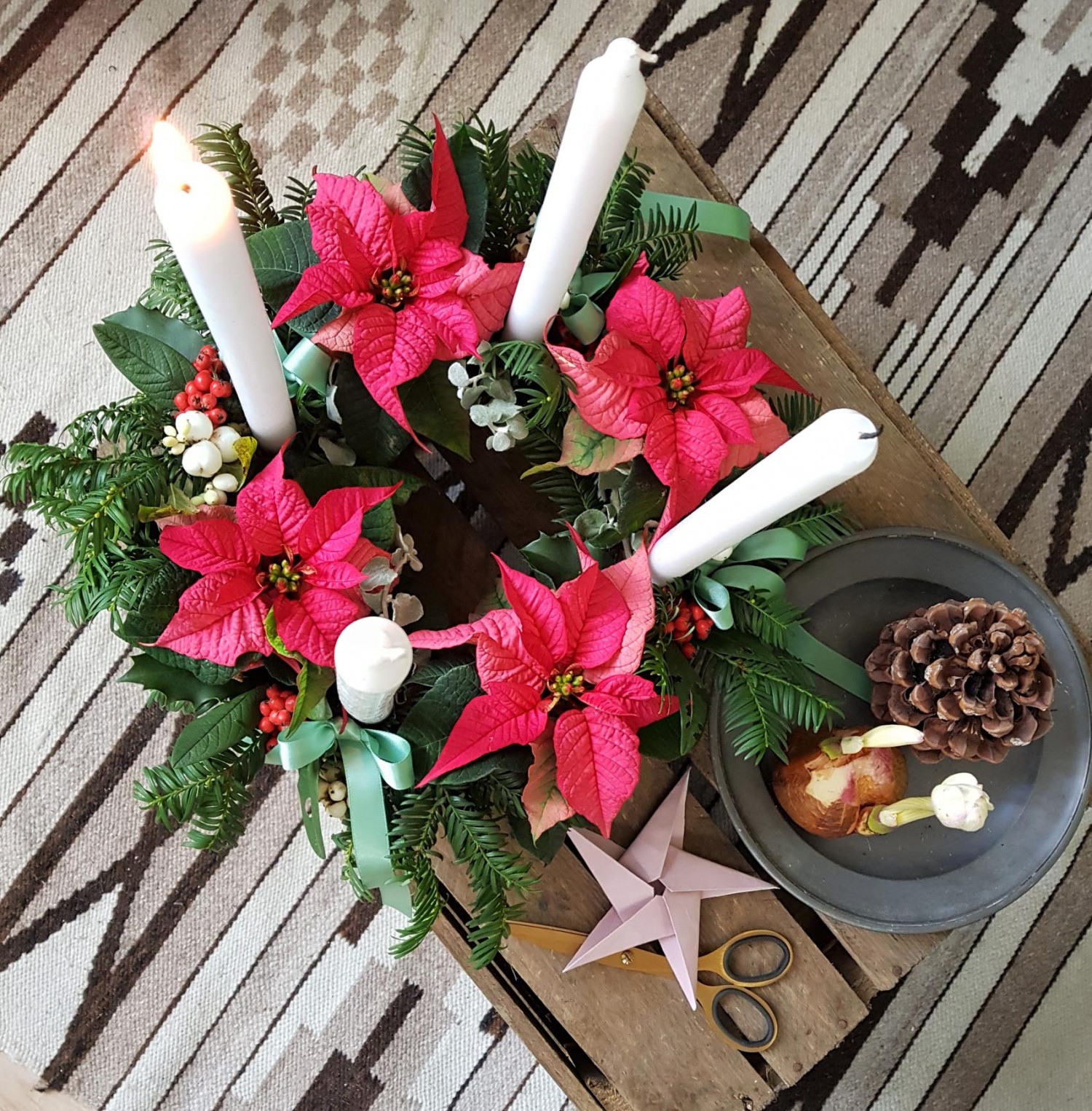 The advent wreath seen from above. The dark pink poinsettia is giving the wreath a colourful twist.