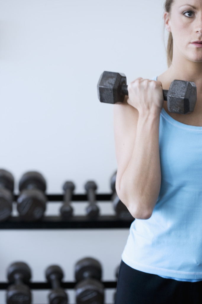 Arnold press Woman Curling Dumbbells --- Image by © Royalty-Free/Corbis