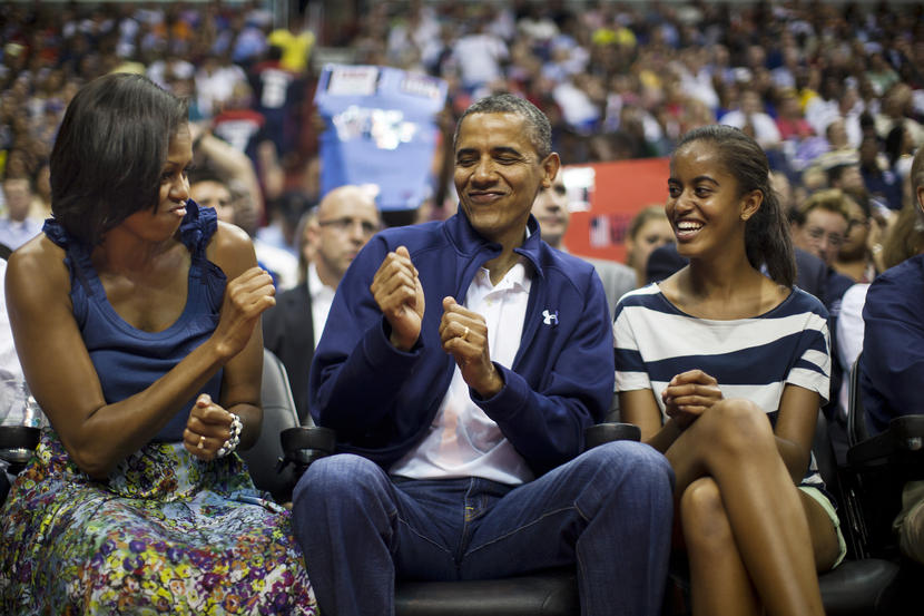 epa03308465 US President Barack Obama (C) does a little dance while First Lady Michelle Obama (L) and the President's daughter Malia(R) look on as they attend an exhibition basketball game between the USA and Brazil at the Verizon Center in Washington DC, USA, 16 July 2012. The President is back on the campaign trail on 17 July with a day-trip to Texas. EPA/JIM LO SCALZO