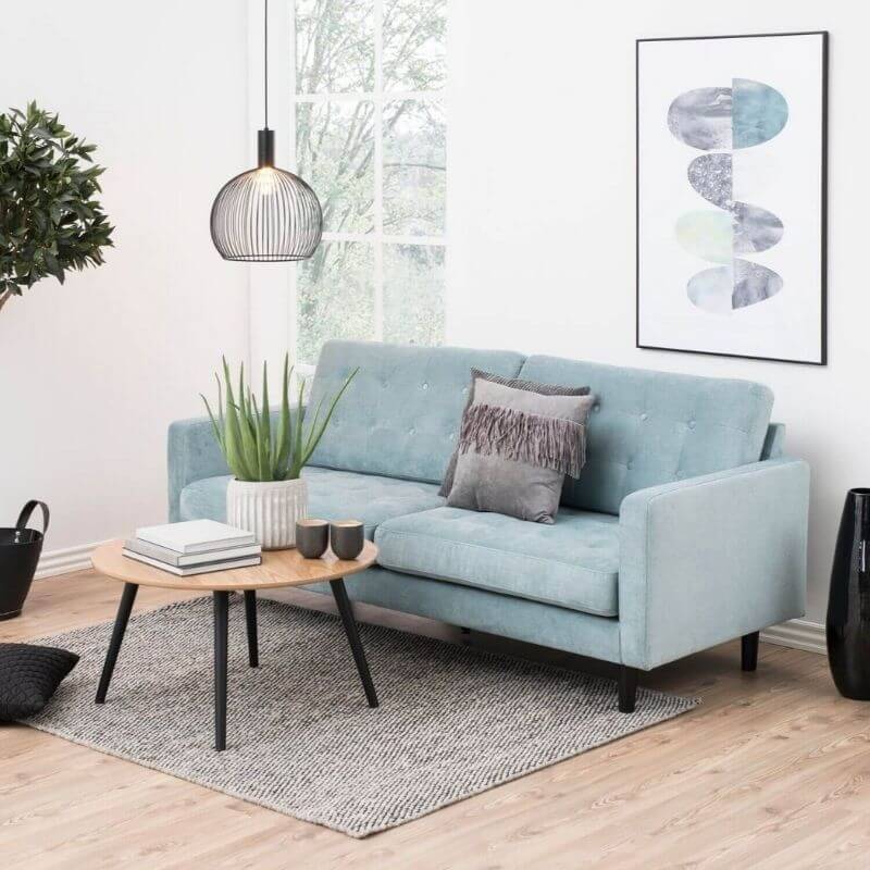Lys stue med blå sofa og rundt sofabord